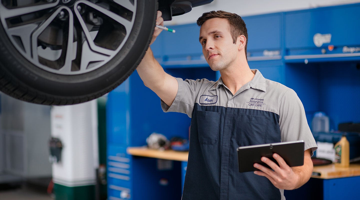 Hyundai service technician inspecting a vehicle in a dealership service center